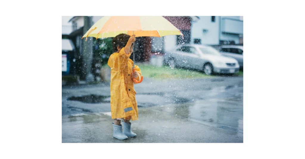 A child with an umbrella in heavy rain.